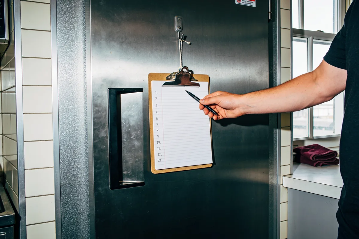 Eine leere HACCP-Checkliste an einem Haken neben einer Kühlraumtür