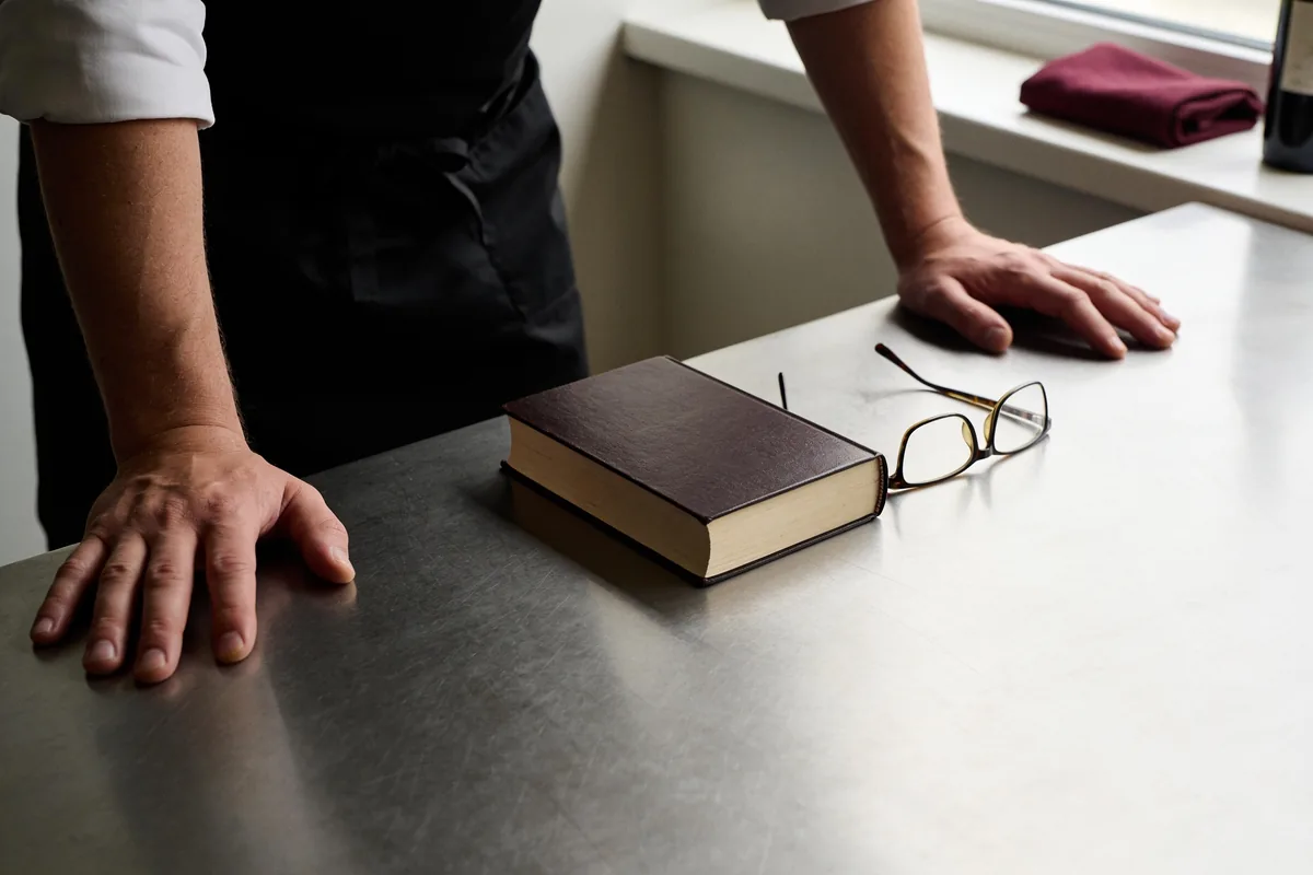 Ein geschlossenes Gesetzbuch neben einer Lesebrille auf einem Schreibtisch
