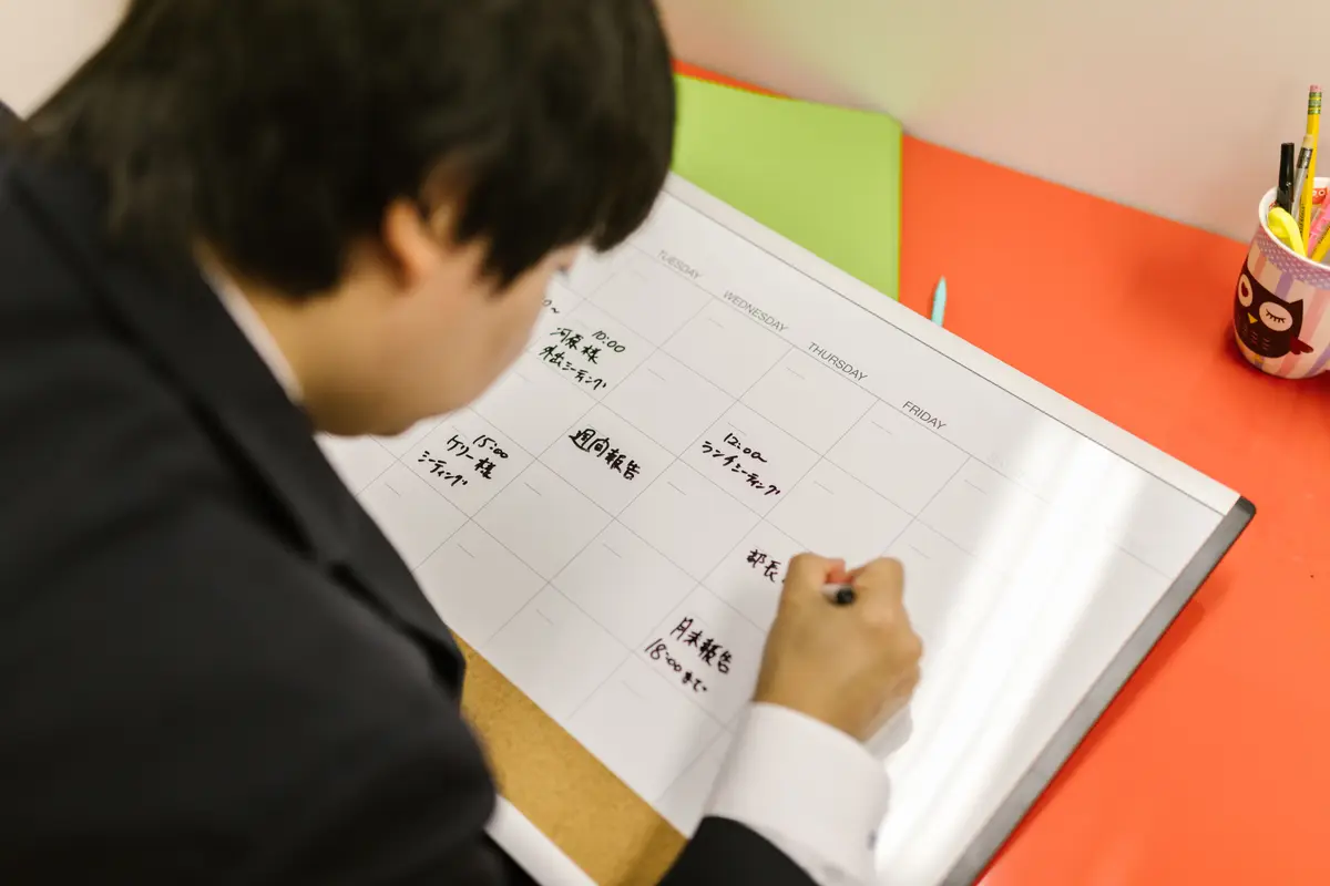 Person plant einen Wochenplan auf dem Schreibtisch